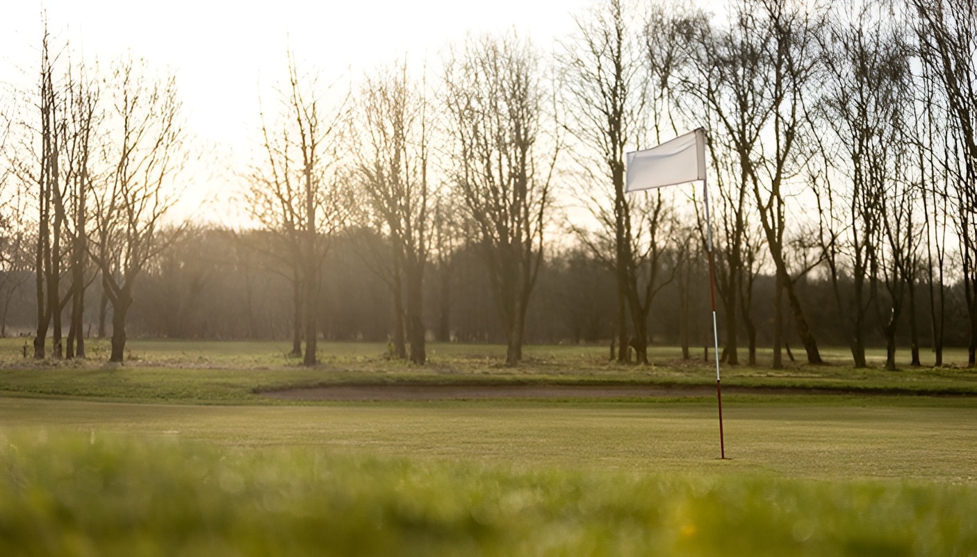 Two golfers with bags walk on a grassy field
